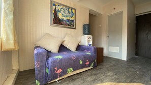 A room with a sofa, a water dispenser, and a door.