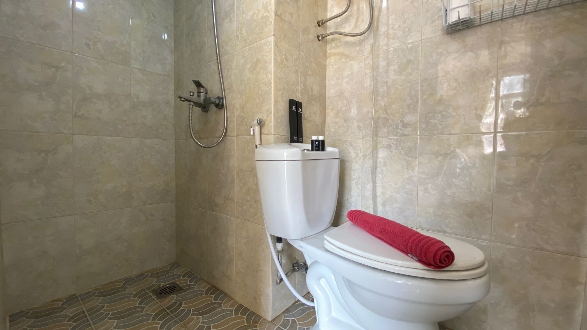 Een badkamer met toilet, douche en betegelde vloer.