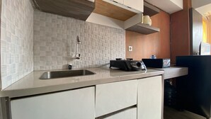 A modern kitchen with a stainless steel sink, a built-in microwave, and a coffee machine. - Comfortable And Simply Modern 2Br Apartment At The Jarrdin Cihampelas (Bandung)
