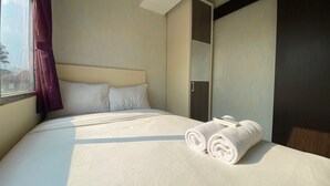 A hotel room with a bed, a window with curtains, and a mirror. - Comfortable And Simply Modern 2Br Apartment At The Jarrdin Cihampelas (Bandung)