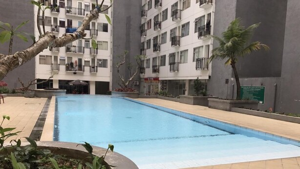 A swimming pool surrounded by a building with balconies. - Comfortable And Simply Modern 2Br Apartment At The Jarrdin Cihampelas (Bandung)