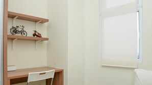 A room with a wooden desk, a white chair, and shelves with a bicycle and a toy horse. - 2Br Yotayori Home At Green Pramuka City Apartment (Jakarta)