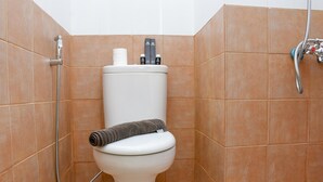 A bathroom with a toilet, a shower, and a towel rack. - 2Br Yotayori Home At Green Pramuka City Apartment (Jakarta)