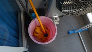 A pink bucket with orange items, a blue broom, and a fan. - Exquisite Studio Apartment At Tamansari Papilio (Surabaya)
