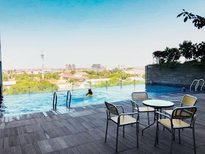 An outdoor pool area with a view of a cityscape, including buildings and a tower.