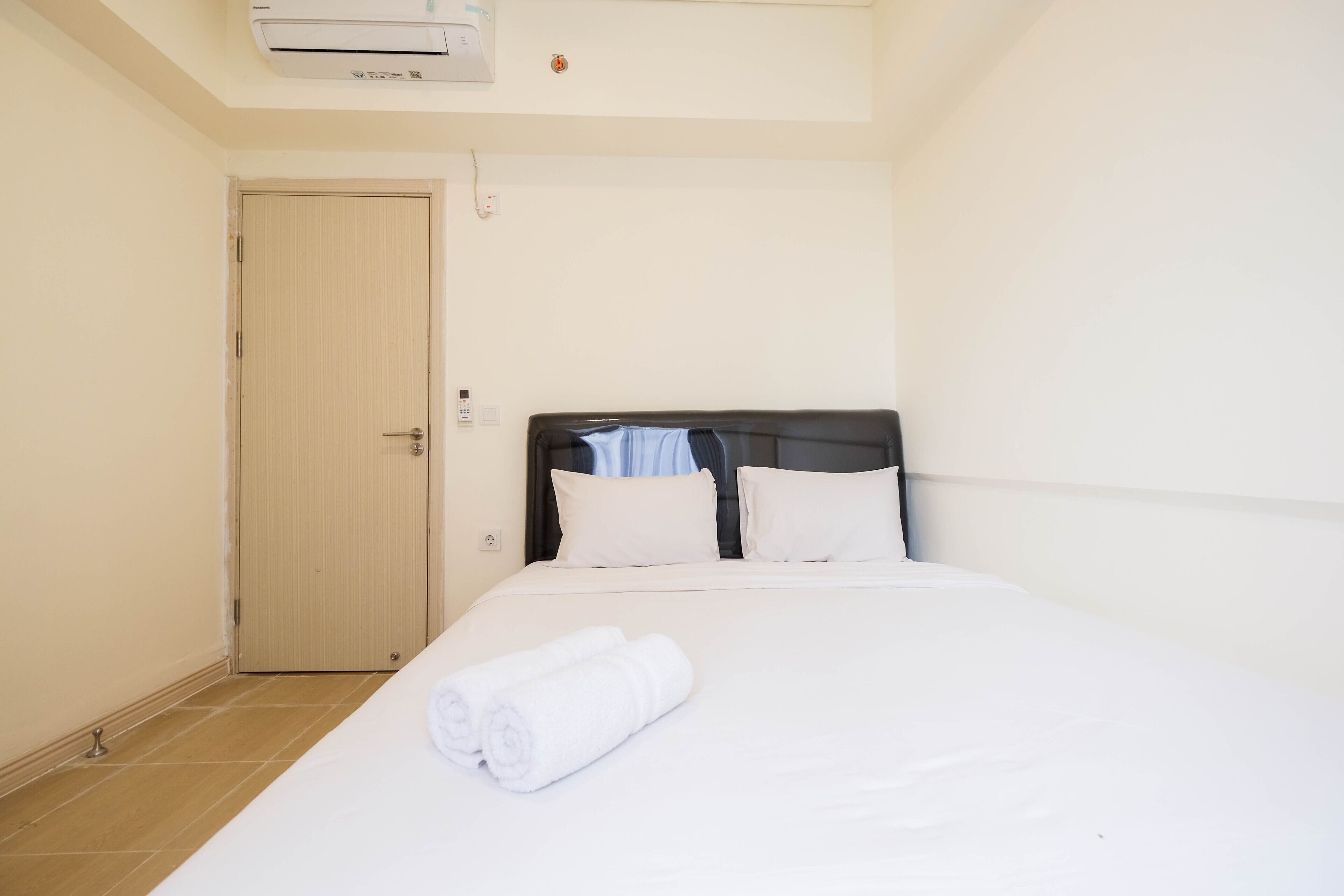 Une chambre d’hôtel avec un lit, une porte et un appareil de climatisation.