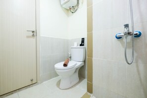 Une salle de bain avec des toilettes, une douche et une serviette posée sur le siège.