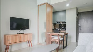 A modern living room with a flat-screen TV, a wooden cabinet, a dining table with chairs, and a sofa.