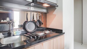 A modern kitchen with stainless steel appliances, a black countertop, and hanging pots.