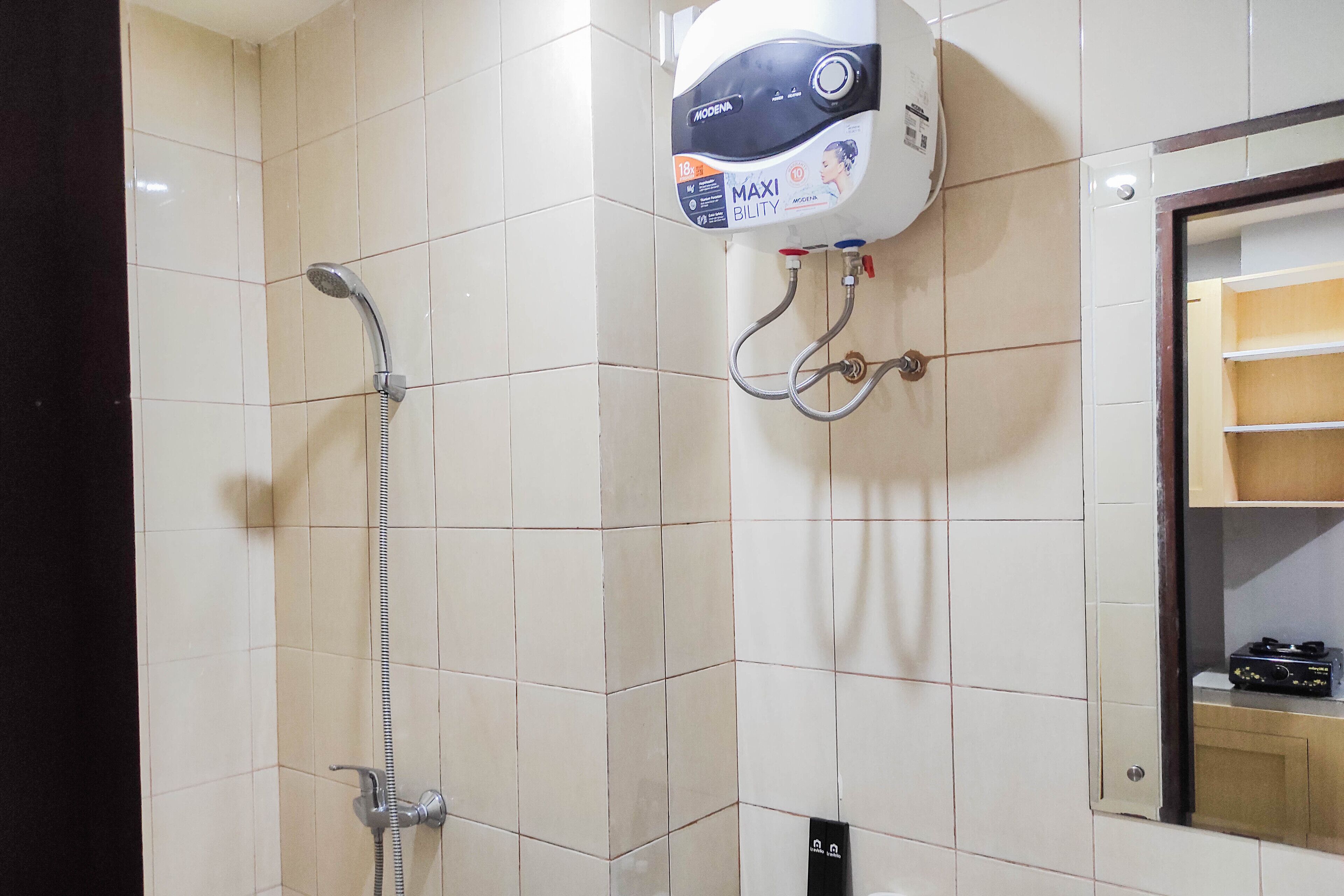A bathroom with a shower, a water heater, and a mirror.