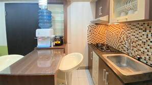 A modern kitchen with a water dispenser, a microwave, a gas stove, and a sink. - Cozy & Pleasant 2Br Apartment At The Jarrdin Cihampelas (Bandung)