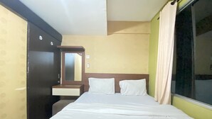 A hotel room with a bed, a nightstand, a mirror, and a window with curtains. - Cozy & Pleasant 2Br Apartment At The Jarrdin Cihampelas (Bandung)
