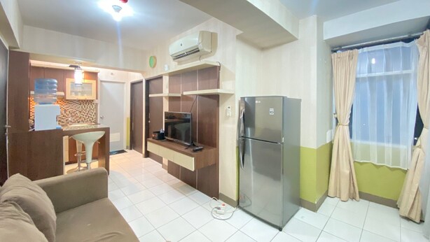 A compact living space with a kitchenette, a sofa, a TV, and a refrigerator. - Cozy & Pleasant 2Br Apartment At The Jarrdin Cihampelas (Bandung)