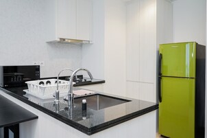 A modern kitchen with a black countertop, stainless steel sink, and a green refrigerator.