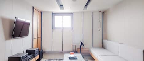 A modern living room with a flat-screen TV, a sofa, a coffee table, and a sound system.