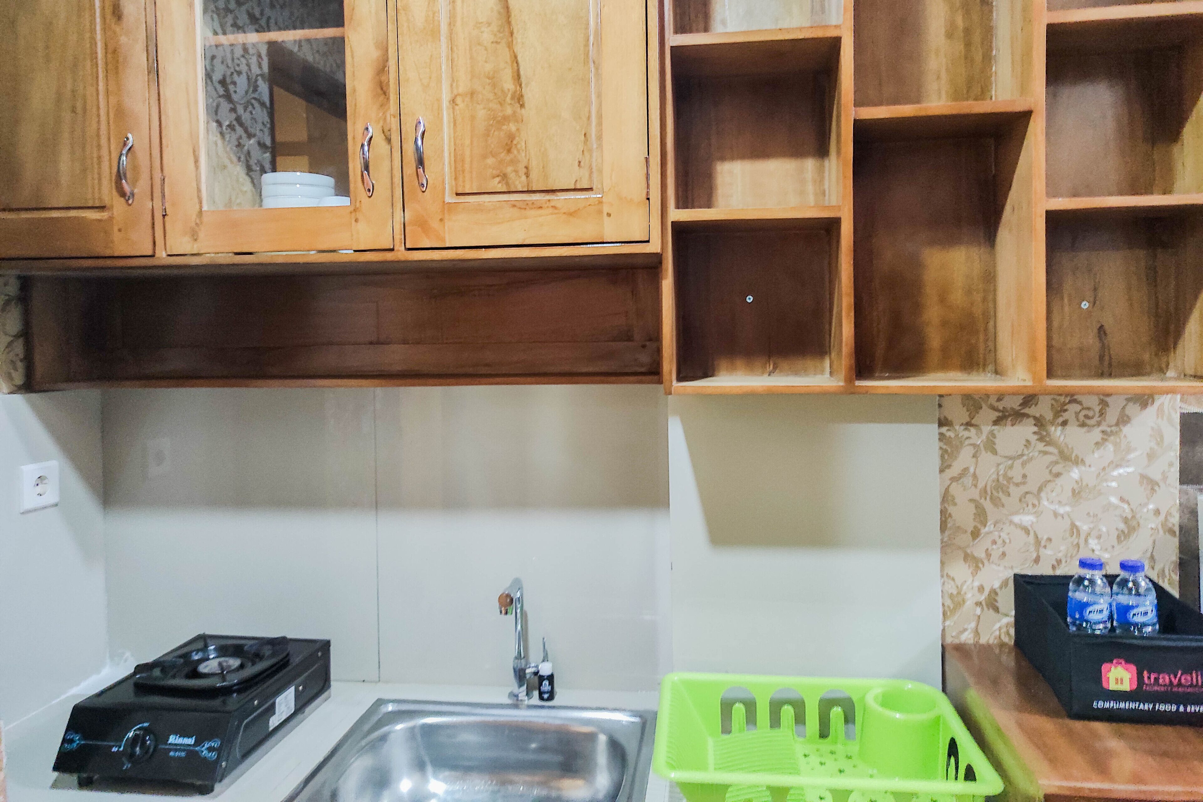 A kitchen with wooden cabinets, a gas stove, a sink, and a green dish rack.