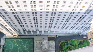 An aerial view of a high-rise building with multiple balconies, a basketball court, and a road with vehicles. - Alluring 2Br At Bassura City Apartment Near Mall (Jakarta)