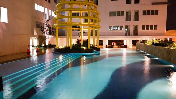 A pool area with a yellow structure, surrounded by a building with multiple windows. - Comfort Living Bassura City Studio Apartment Near Mall (Jakarta)