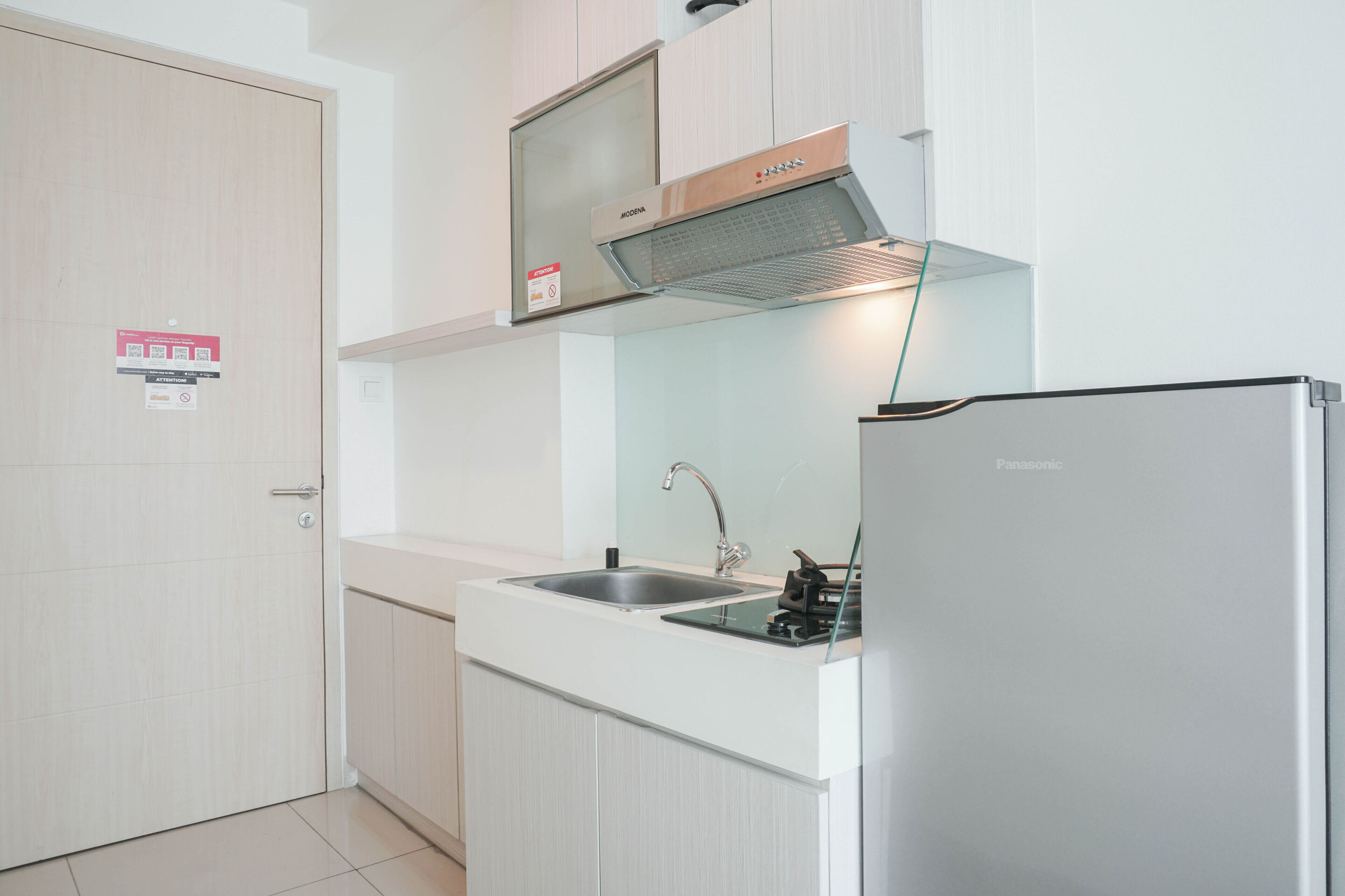 A modern kitchen with a stainless steel sink, a built-in stove, and a Panasonic refrigerator.