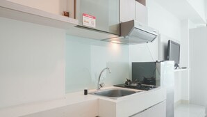 A modern kitchen with a stainless steel sink, a gas stove, and a microwave. - Comfortable Studio Room At Tree Park Bsd Apartment (South Tangerang)