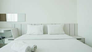 A modern hotel room with a neatly made bed, a desk, and a chair. - Comfortable Studio Room At Tree Park Bsd Apartment (South Tangerang)