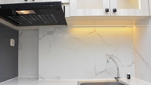 Una cuina moderna amb salabost d'àmbig, rentapeus d'acer inoxidable i campana extractora negra.