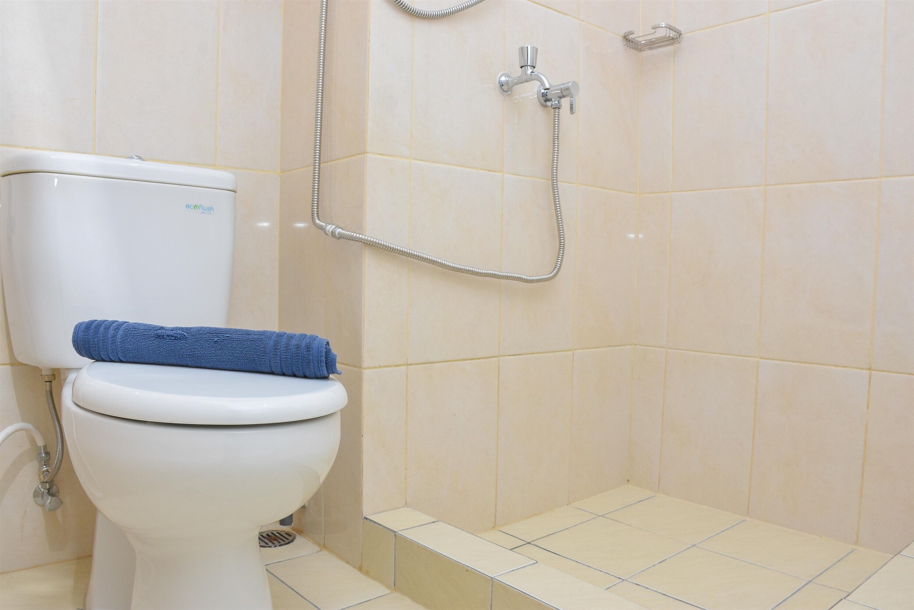 A bathroom with a toilet, a shower, and a towel on the toilet.