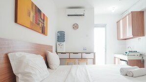 Une chambre d’hôtel avec un lit, un petit bureau, un distributeur d’eau, un climatiseur et une horloge murale.