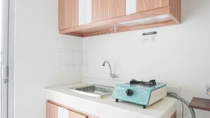 Une petite cuisine équipée de meubles en bois, d’un évier, d’une cuisinière à gaz portable et d’une prise de courant.