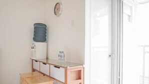 Une petite pièce avec un bureau en bois, un distributeur d’eau et une horloge au mur.