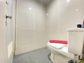 Bathroom features a toilet and shower area with a drain.