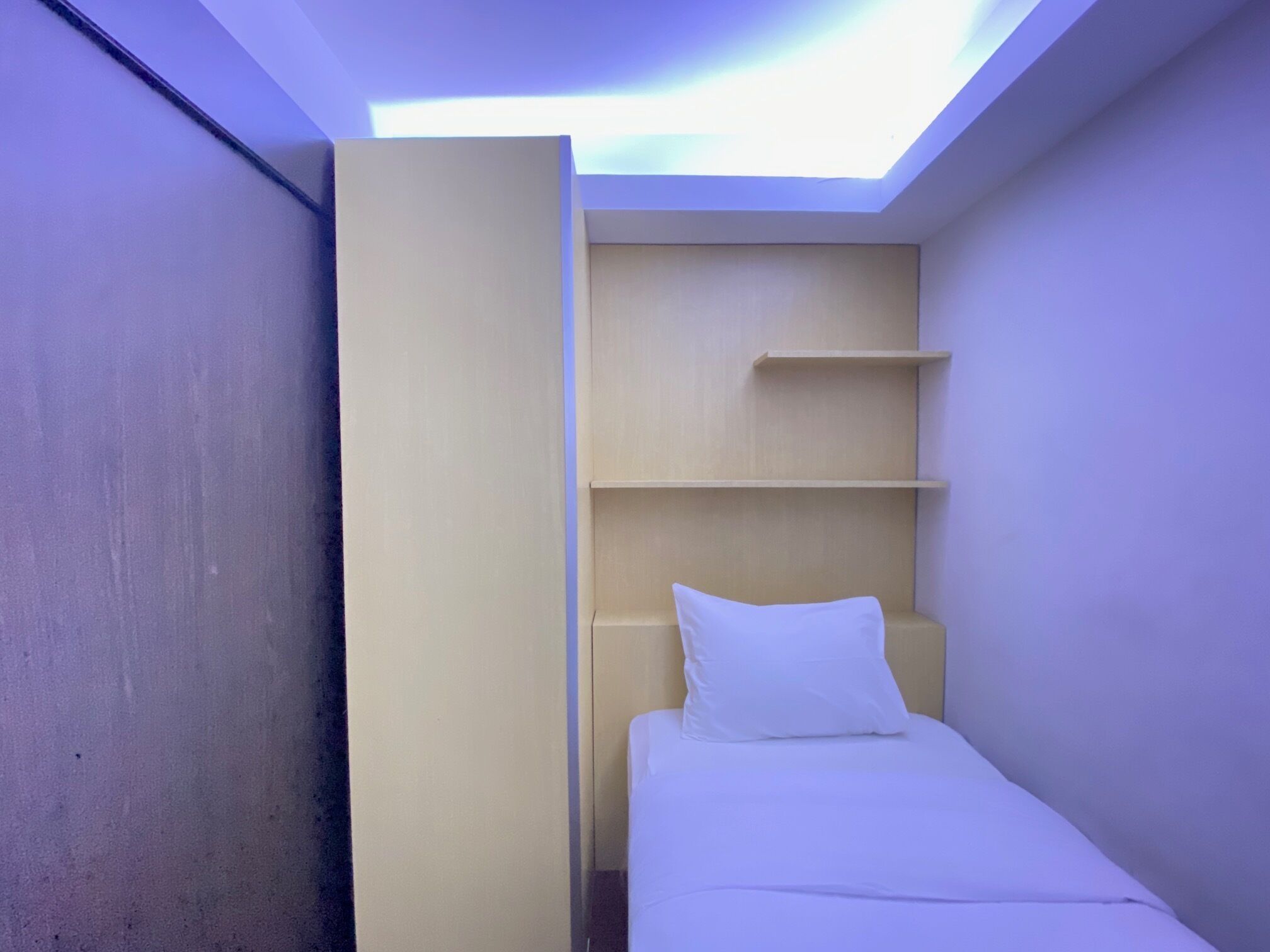 A small, modern room with a skylight, a bed, and built-in shelves.