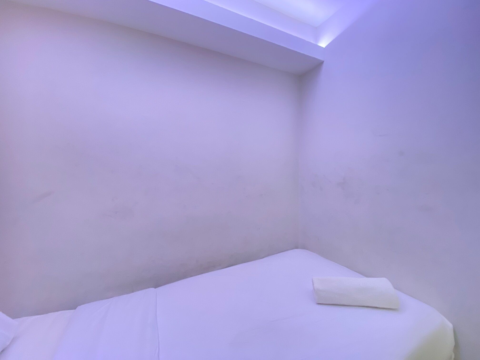 A small, dimly lit room with a single bed and a skylight.