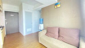 A living room with a beige sofa, a water dispenser, and a large water bottle on a stand. - Quite 2Br Apartment Ac In Living Room At The Jarrdin Cihampelas (Bandung)