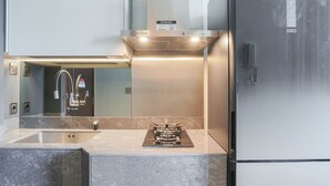 A modern kitchen with a built-in gas stove, stainless steel appliances, and a large refrigerator. - Great Choice Deluxe Studio Apartment At Capitol Park Residence (Jakarta)