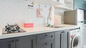 A modern kitchen with a gas stove, a washing machine, and a sink. - Minimalist Studio Room With City View At West Vista Apartment (Jakarta)
