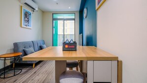 A modern room with a wooden table, a grey sofa, a small round table, and a blue wall. - Simply 1Br Apartment At Pejaten Park Residence (Jakarta)