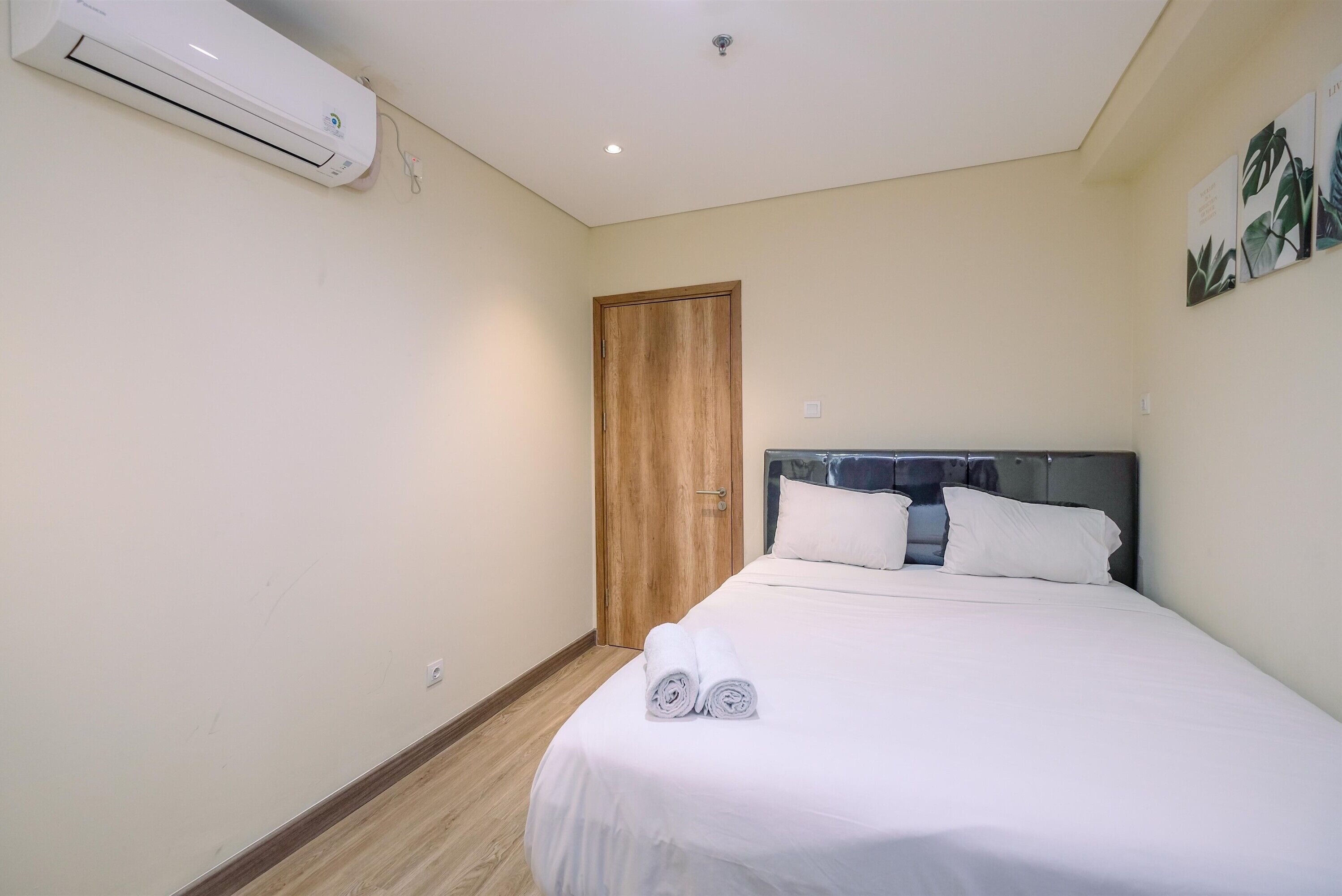 A bedroom with a bed, a wooden door, and an air conditioning unit.
