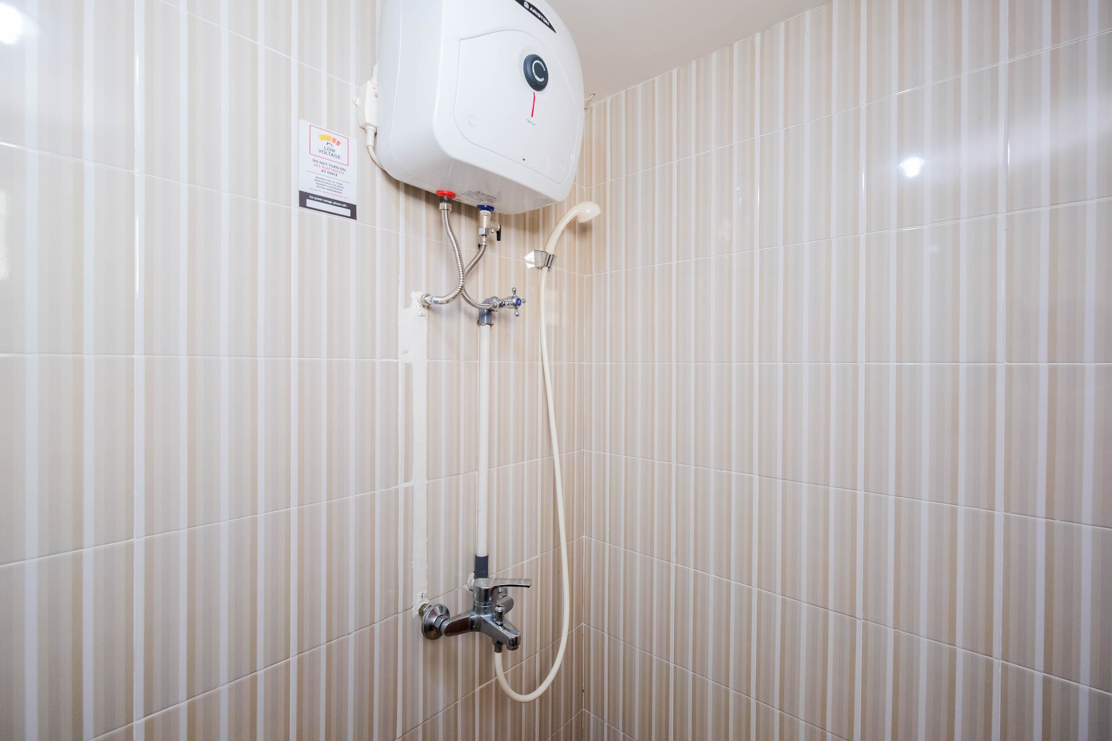 A bathroom with a wall-mounted water heater, a showerhead, and a handheld shower attachment.