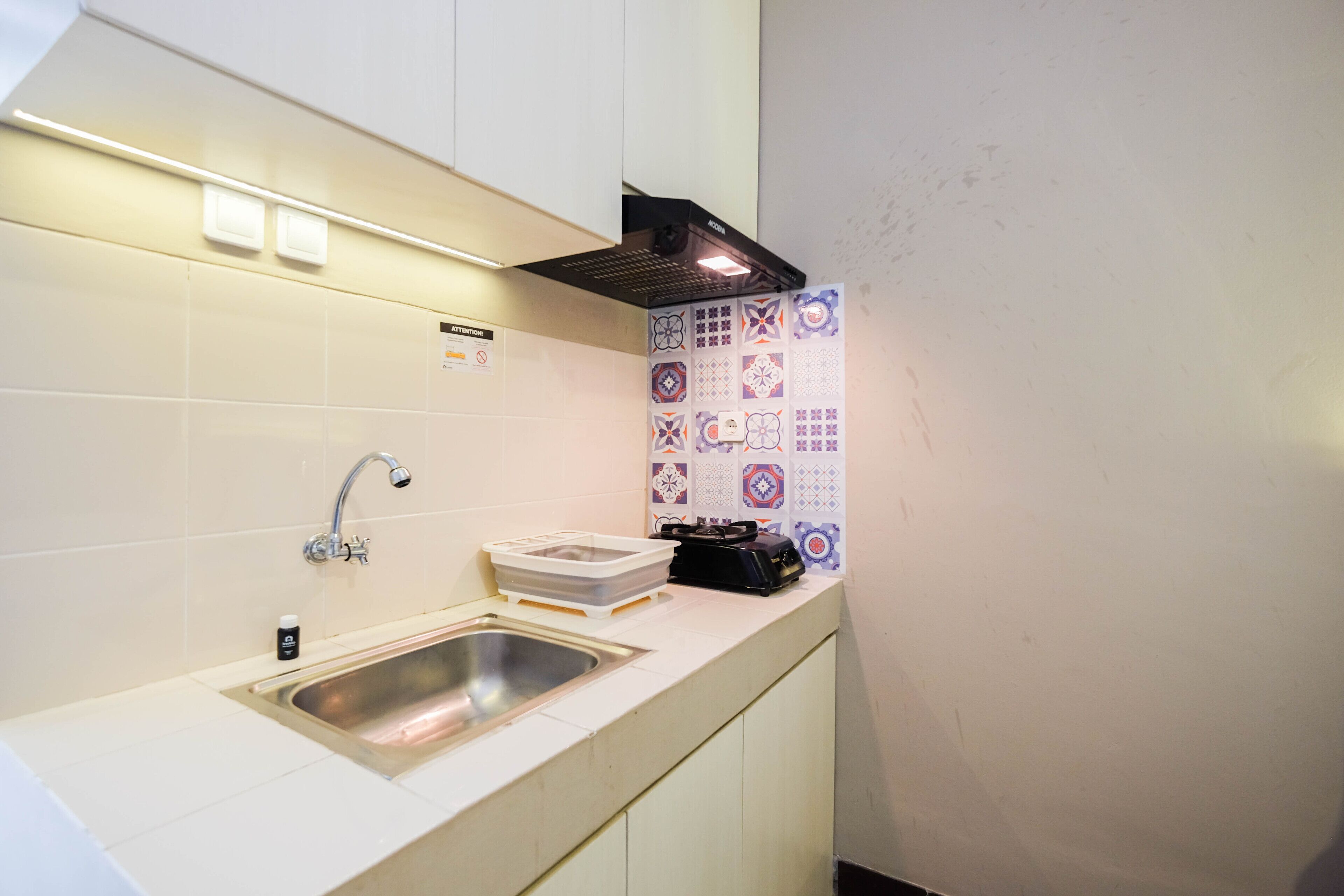 A compact kitchen with a stainless steel sink, a faucet, a microwave, and a small countertop.