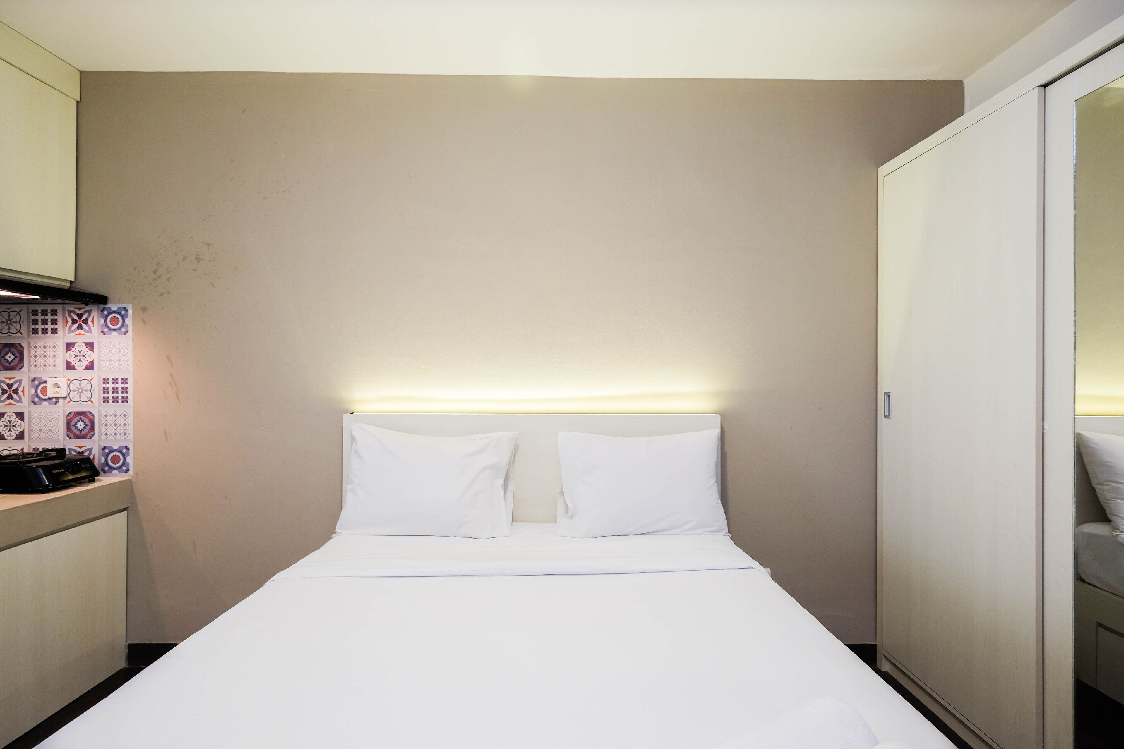 A hotel room with a bed, a bedside table, and a wardrobe.
