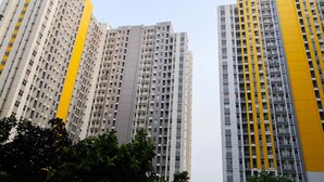 Een hoog appartementencomplex met meerdere balkons en een geel accent aan één kant.