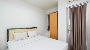 Ein Hotelzimmer mit einem Bett, einer Holztür und einem Fenster mit Vorhängen.