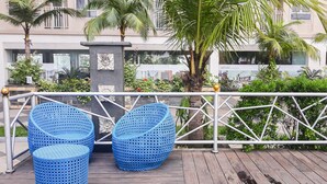 Eine Holzterrasse mit zwei blauen Sitzgelegenheiten aus Gewebe und einer kleinen Mülltonne.