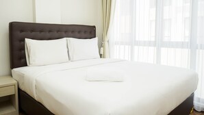 Un lit bien fait, avec des draps blancs, une tête de lit sombre et un oreiller blanc.