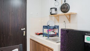 A compact kitchen with a wooden cabinet, a countertop, a sink, and a stove. - Nice And Spacious Studio At Serpong Greenview Apartment (South Tangerang)