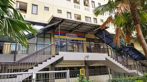 Um edifício de vários andares com uma placa Indomaret bem visível, escadas externas e uma palmeira.