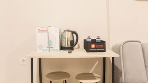 A small kitchenette area with a coffee maker, a box labeled 'Cosmos', and a 'Travalio' beverage cooler. - Great Choice 2Br Apartment At Meikarta (Cikarang)