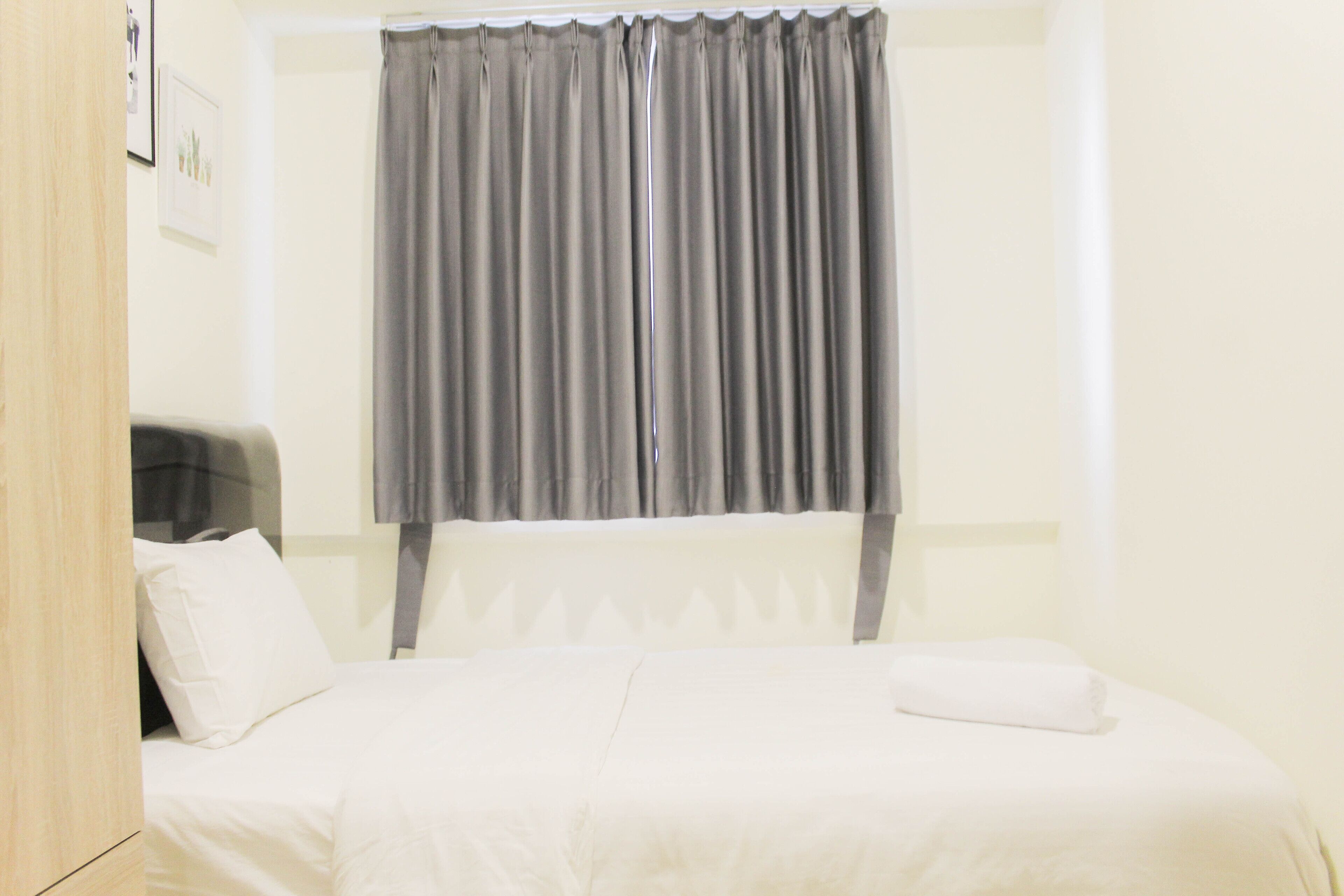 Quarto de hotel com cama, cabeceira, mesa de cabeceira e cortina.