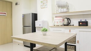 A kitchen with a wooden table, a refrigerator, a coffee maker, and a small potted plant.